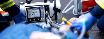 Primer plano de un ventilador WEINMANN durante una operación de rescate. En primer plano, un herido recibe tratamiento médico.