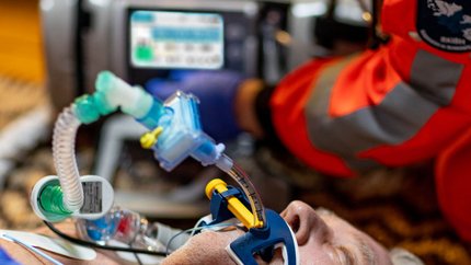 Atemwegsmanagement Eine verletzte Person liegt auf dem Boden und wird künstlich beatmet. Ein Rettungsteam nutzt ein Beatmungsgerät, um die Person zu versorgen.